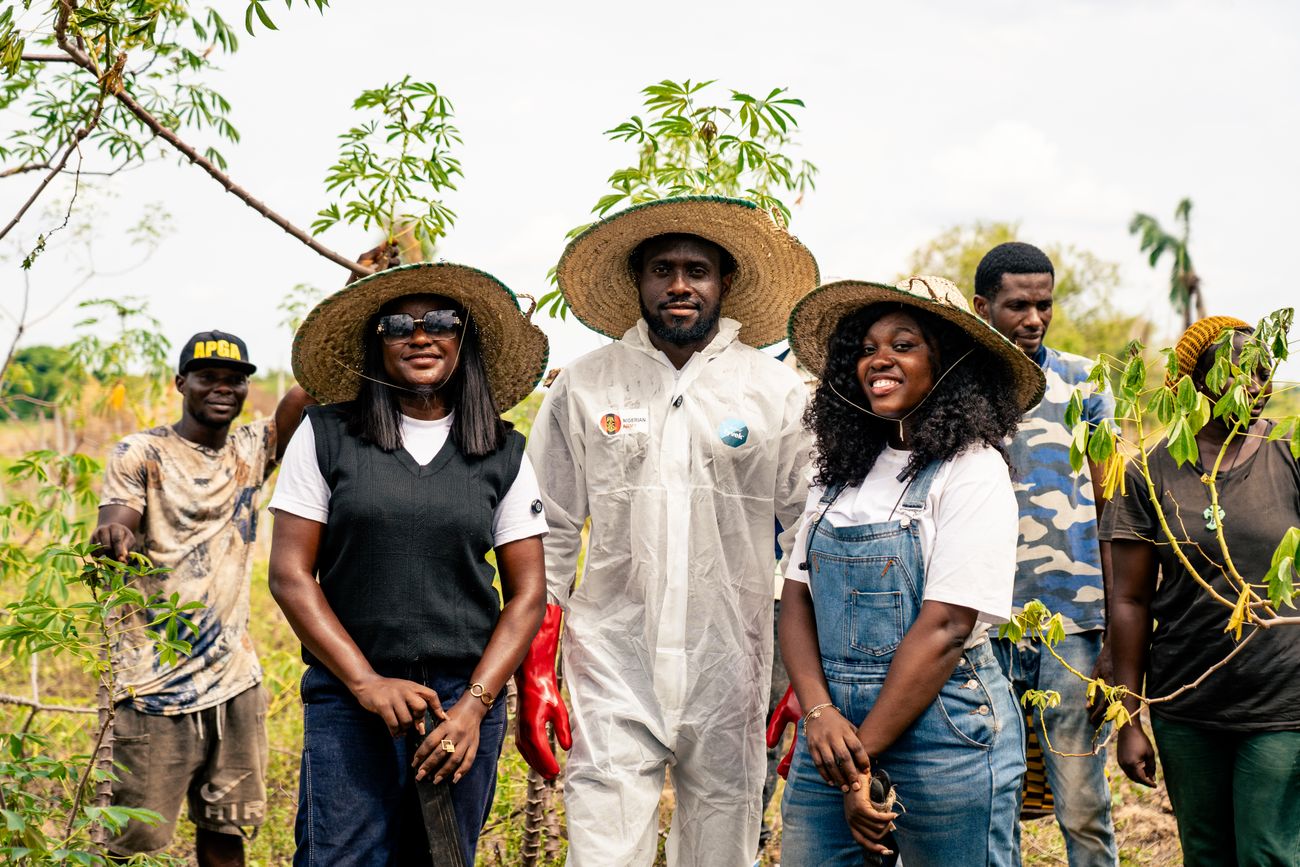 A group of young farmers standing together at the edge of a cultivated field.